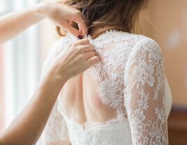 Bride putting on wedding dress