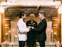 Grooms at altar during ceremony with officiant.