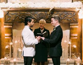 Grooms at altar during ceremony with officiant.