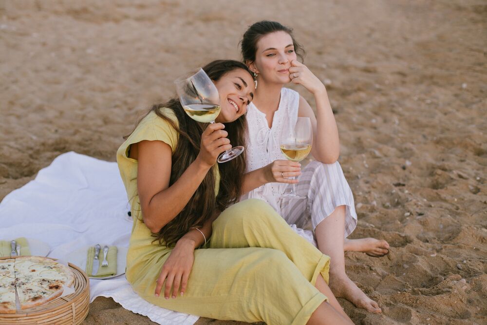 two friends on the beach drinking white wine