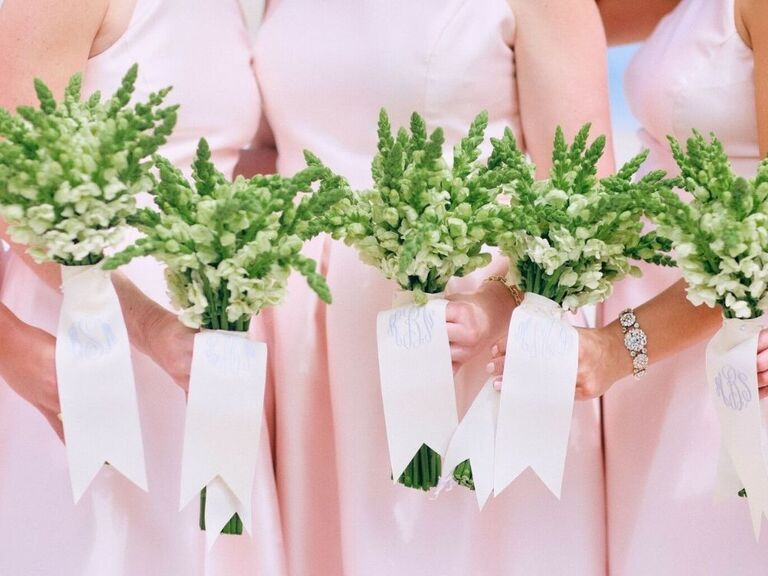 bridesmaids in pink dresses holding green snapdragon bouquets tied with monogrammed ribbon