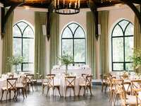 ballroom wedding venue with high ceilings, iron chandelier and green fabric drapes