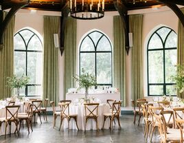 ballroom wedding venue with high ceilings, iron chandelier and green fabric drapes