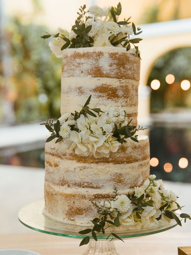 two tier vanilla semi naked wedding cake decorated with white flowers and greenery