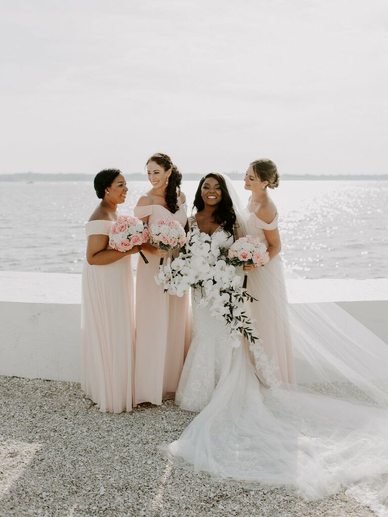 Bridesmaids wear pale pink off-the-shoulder gowns. 