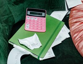 Image of a pink calculator with green notebook and receipts