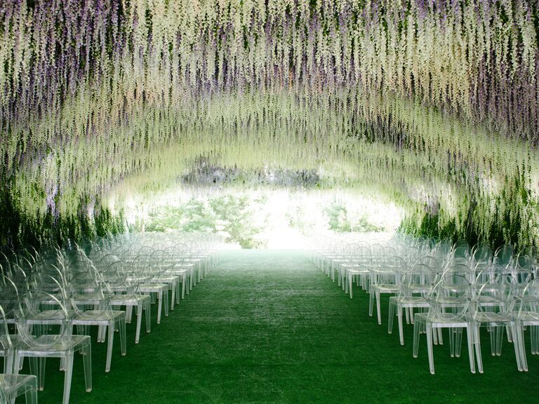 Lush wedding ceremony aisle with thick hanging wisteria over chairs