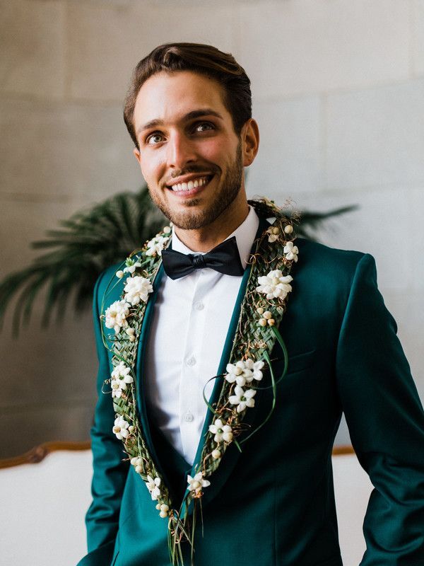 Groom wearing green tuxedo with flowers on collar