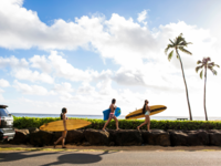 Surfers carrying surfboards on rock wall in Hawaii