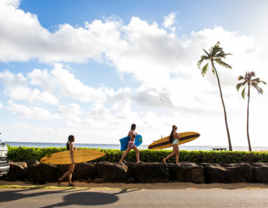 Surfers carrying surfboards on rock wall in Hawaii