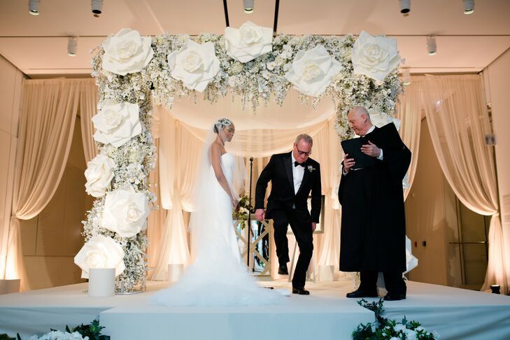 Groom breaking the glass under chuppah with large faux rose decorations
