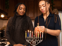 Two Jewish Women Lighting Menorah During Hanukkah Celebration