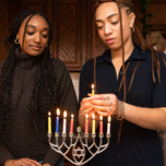 Two Jewish Women Lighting Menorah During Hanukkah Celebration