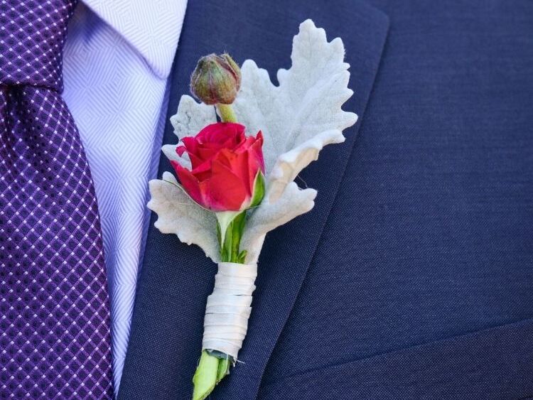 Dusty miller boutonniere on lapel of a navy suit