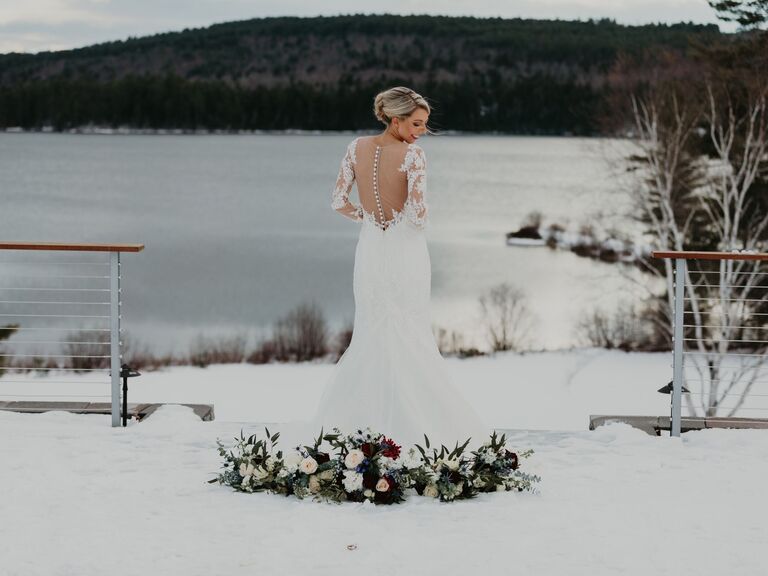 Woman showing the back of her wedding dress in the snowy landscape