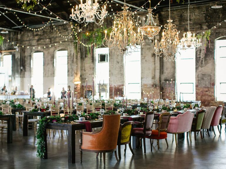 Vintage wedding reception with antique chandeliers, mismatched velvet chairs, candlesticks and string lights