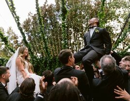 bride and groom being raised on chairs during Jewish hora dance