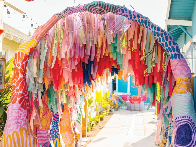 Maximalist wedding arch with colorful materials and strands