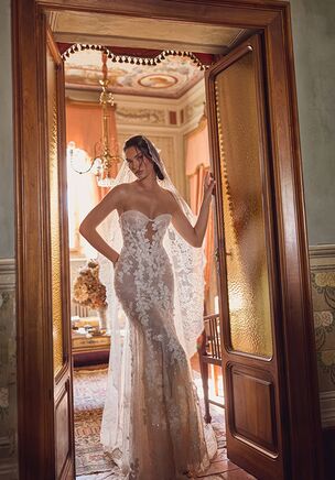 Nyx gown is a refined mermaid silhouette that captivates with its shimmer and floral elegance. Made from sparkling lace, the dress is adorned with delicately scattered floral appliqués that cascade gracefully across the bodice and skirt, creating a romantic, textured effect. The structured bodice features a classic sweetheart neckline with an illusion mesh insert in the center for added support and subtle intrigue. Multiple layers of cappuccino-toned lining add depth and warmth to the overall look, enhancing the lace’s radiance. A distinctive triangular train extends from the skirt, adding drama and sophistication to every step. Nyx is perfect for the bride seeking modern glamor with a timeless floral touch.