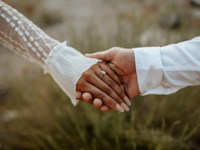 Couple holding hands with engagement ring on