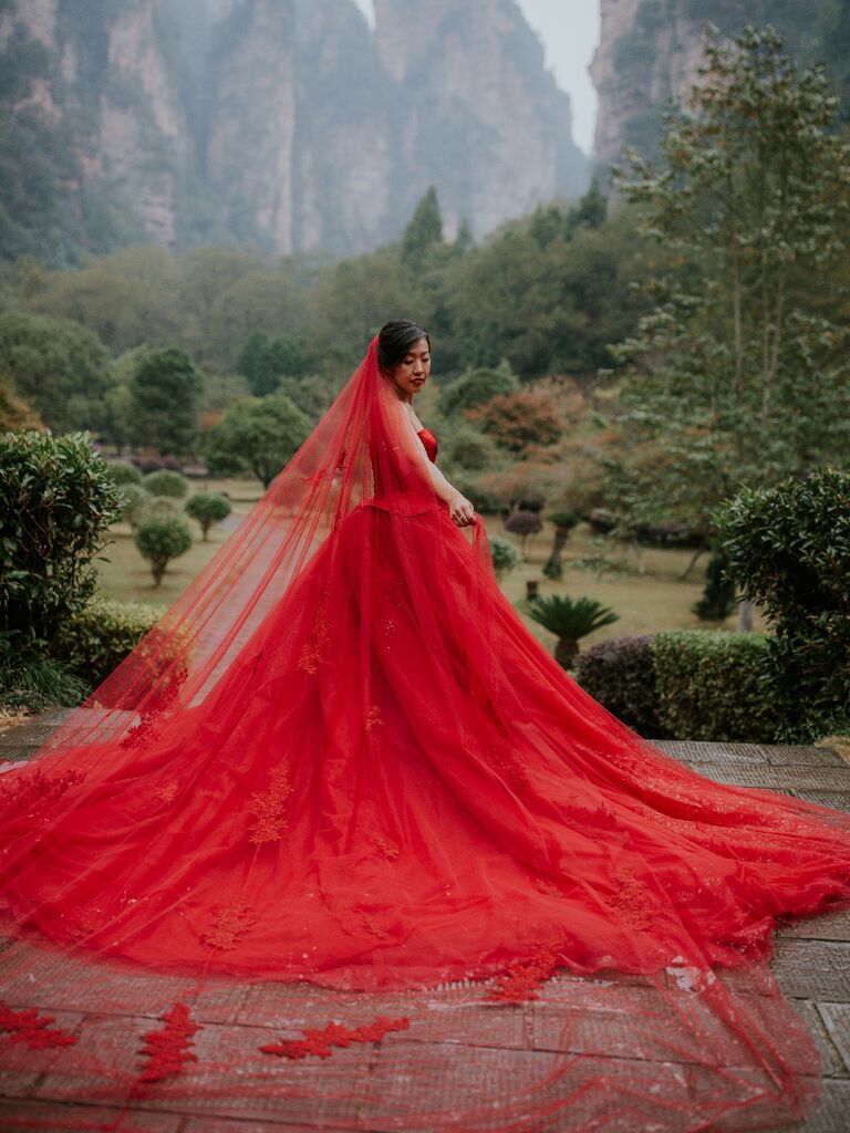 Bride wearing dramatic red ball gown wedding dress with red veil