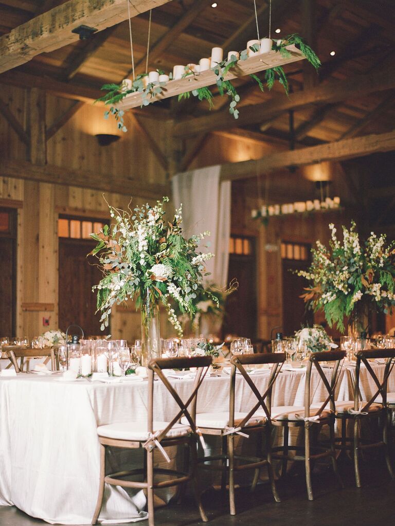 Rustic barn wedding reception with candles on hanging platform above tables