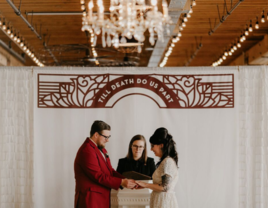 Couple getting married by officiant under 'till death do us part' sign