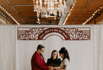 Couple getting married by officiant under 'till death do us part' sign
