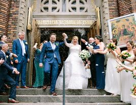 Bride and groom exit church and walk into wedding rice toss. 