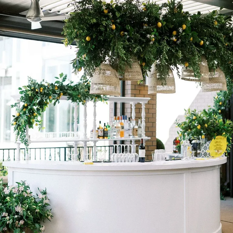 White Rehearsal Dinner Bar With Hanging Lemons, Greenery and Rattan Chandeliers