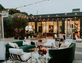 Stunning outdoor event space with comfortable furniture and string lights. 