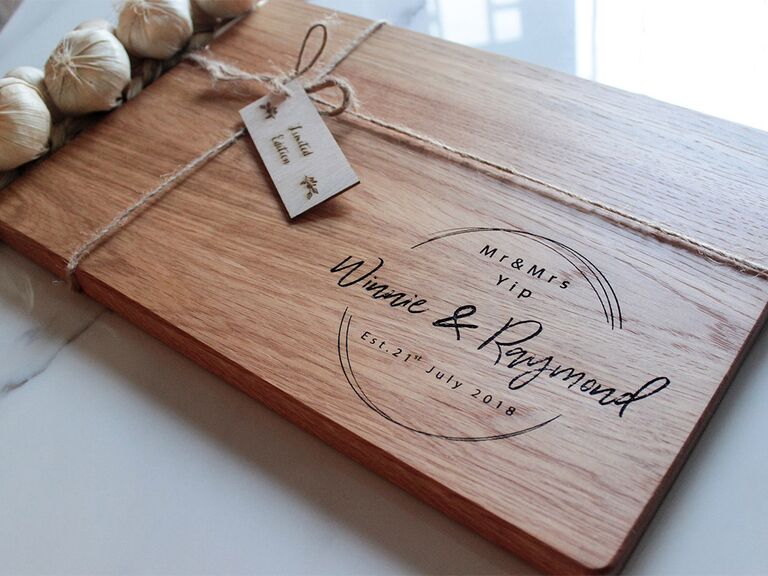 Personalized wooden cutting board with couple's names, date and circle design engraved in bottom right corner