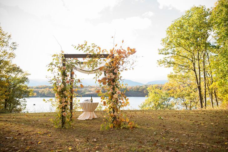 Wood chuppah in a field and covered in greenery vines. 