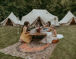 Bride and guests enjoying a picnic outside a tipi