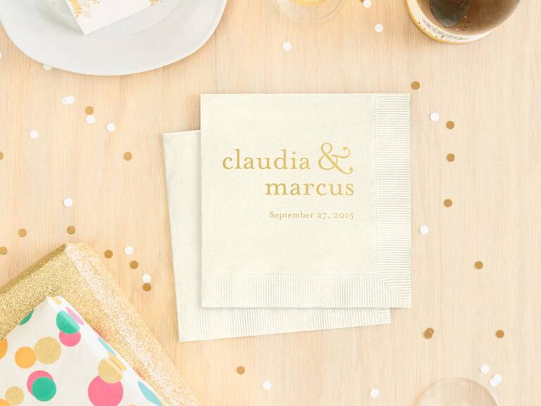 Off-white napkin with names, ampersand and wedding date in playful gold foil type