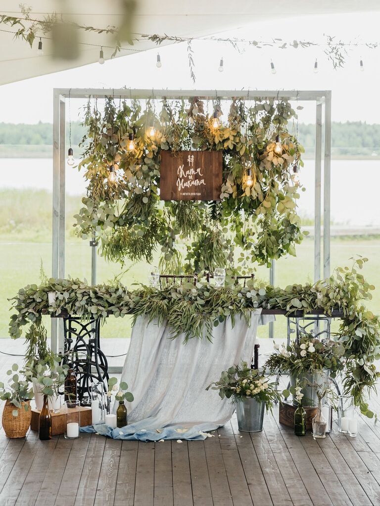 simple wedding sweetheart table decor with bundles of eucalyptus as a backdrop and greenery garland along the front of the table