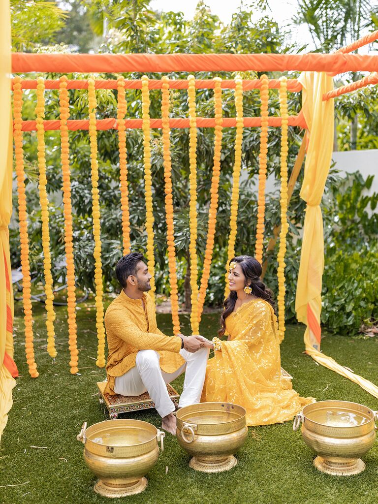 couple seated in front of yellow marigold garlands