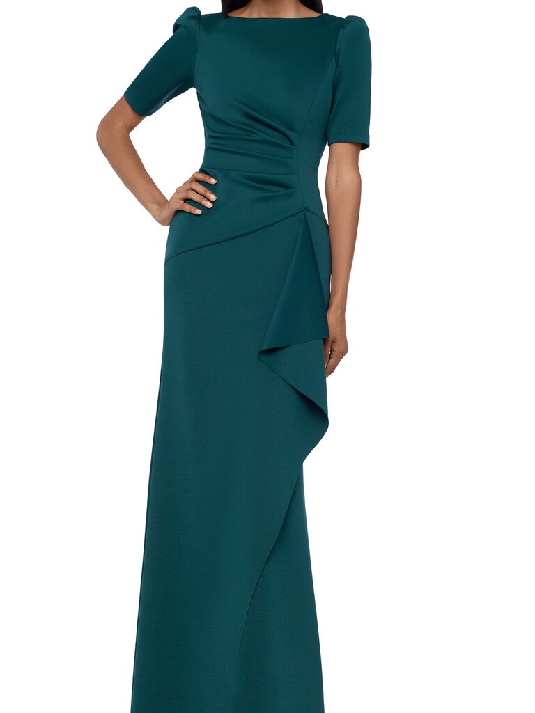 Model wearing green crepe gown with elegant sleeves and ruffles