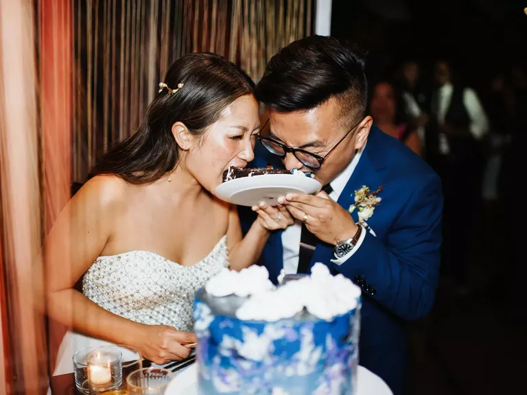 Bride and groom eating cake slice together