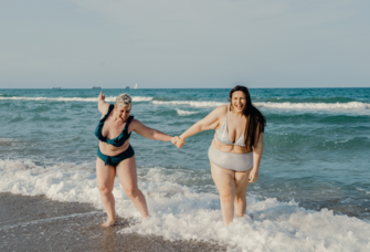 Couple holding hands standing in ocean, best honeymoon destinations in January