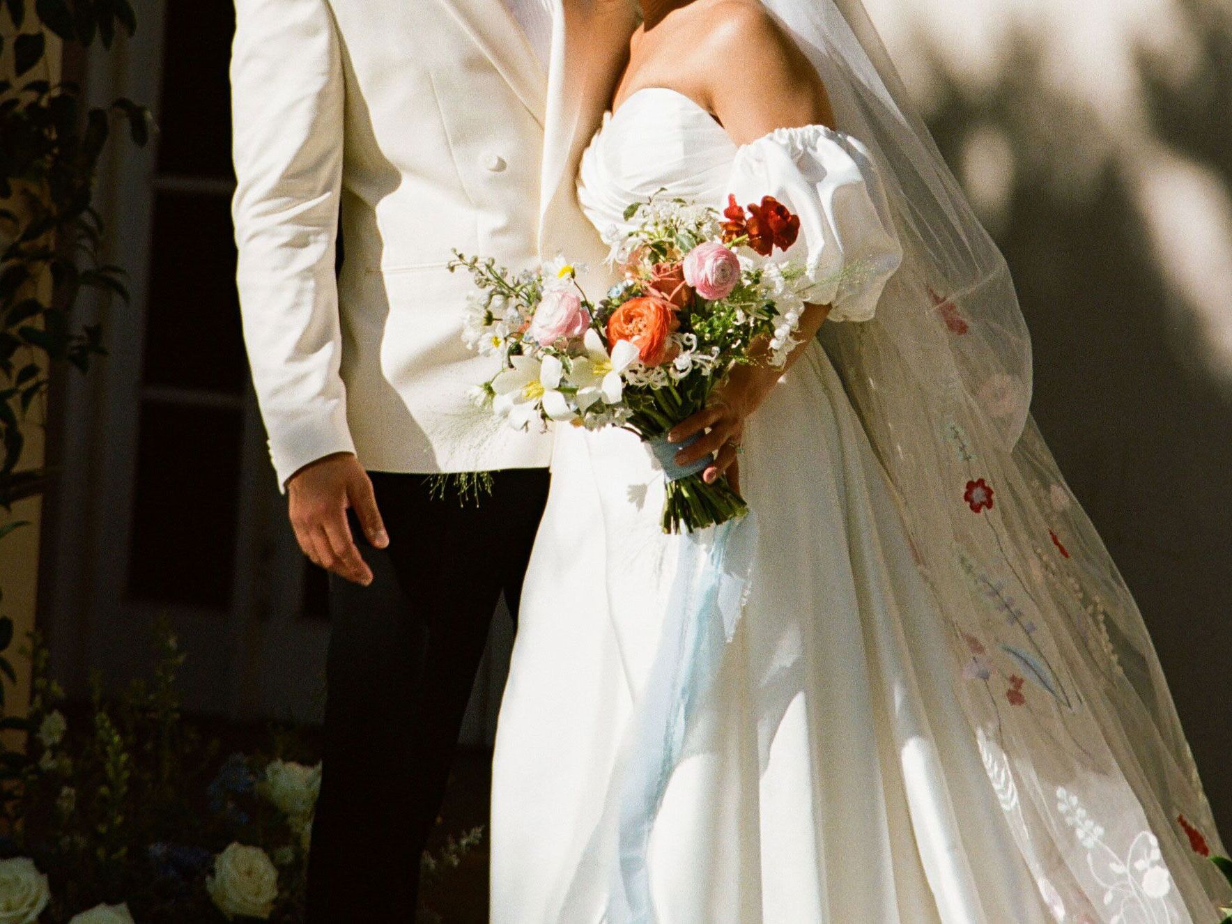 Close-up of couple standing side-by-side with bride holding colorful floral bouquet