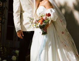 Close-up of couple standing side-by-side with bride holding colorful floral bouquet