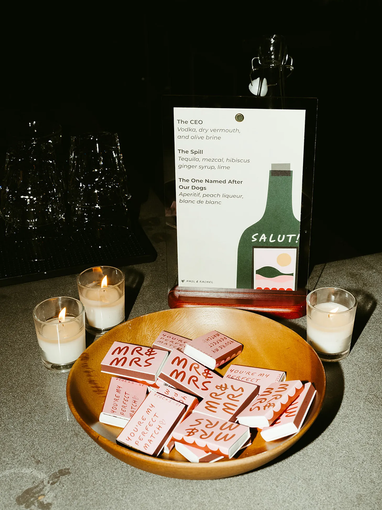Personalized wedding matchboxes in a wooden bowl next to the bar sign