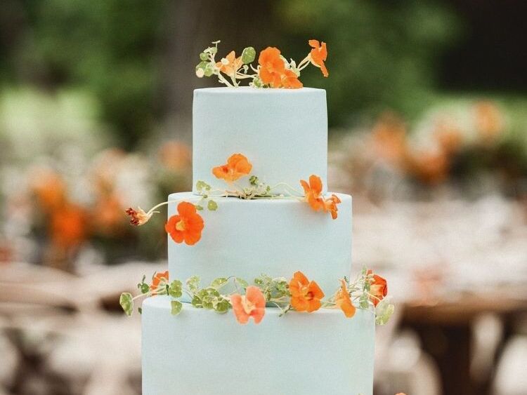 Four-tier blue wedding cake decorated with orange nasturtium blooms