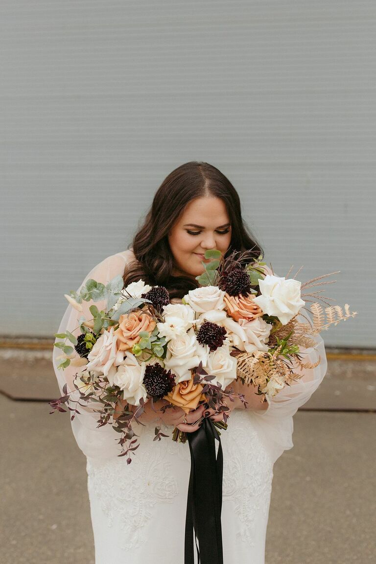 Bride holding bouquet with scabiosa and roses