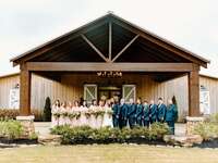 Happy wedding party posing for a picture outside the wooden venue