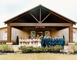 Happy wedding party posing for a picture outside the wooden venue