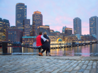 Couple sitting in front of Boston skyline at sunset