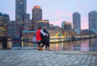 Couple sitting in front of Boston skyline at sunset