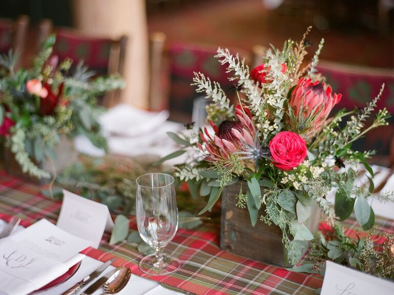 winter wedding centerpiece with red and green plaid table runner and red and green flowers in wooden square vase